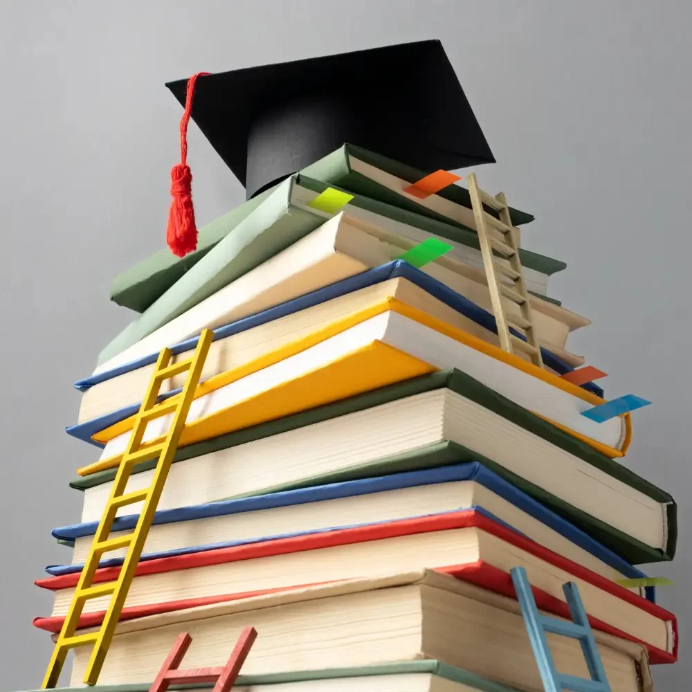 angulo-baixo-de-livros-empilhados-um-bone-de-formatura-e-escadas-para-o-dia-da-educacao